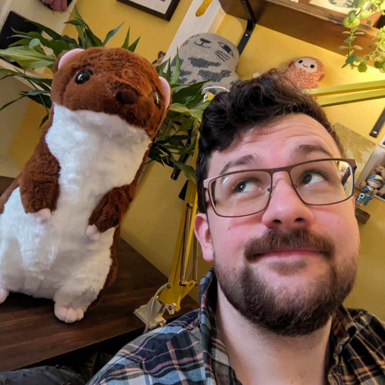 A photo of Brian Tyrrell. He has short black hair, an upper lip moustache, and stubble. He is holding a white labrador in his arms.